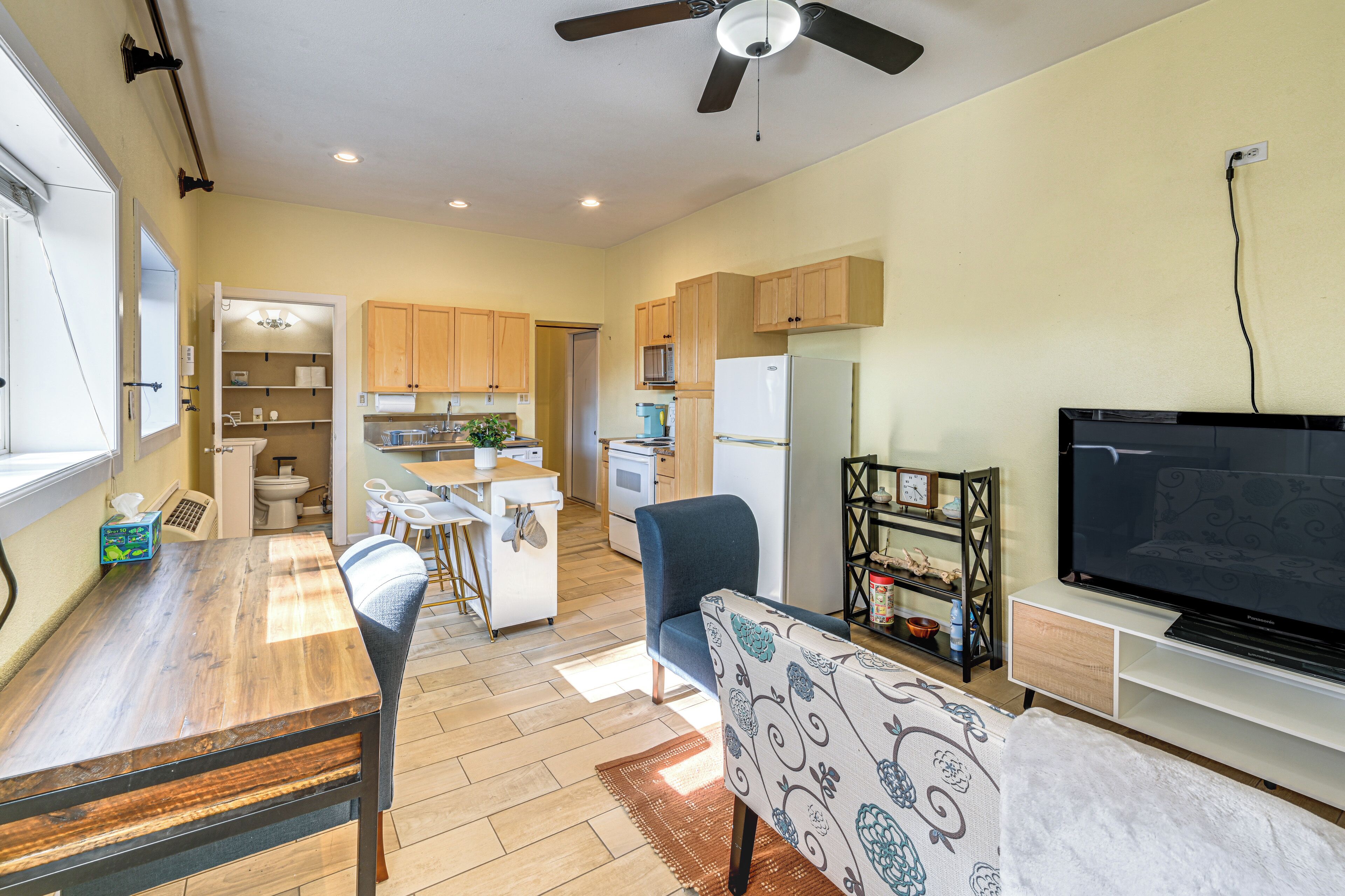 Una cocina moderna con comedor, una sala de estar con televisor de pantalla plana y un ventilador de techo.