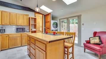 Una cocina moderna con armarios de madera, una isla central y una silla roja.