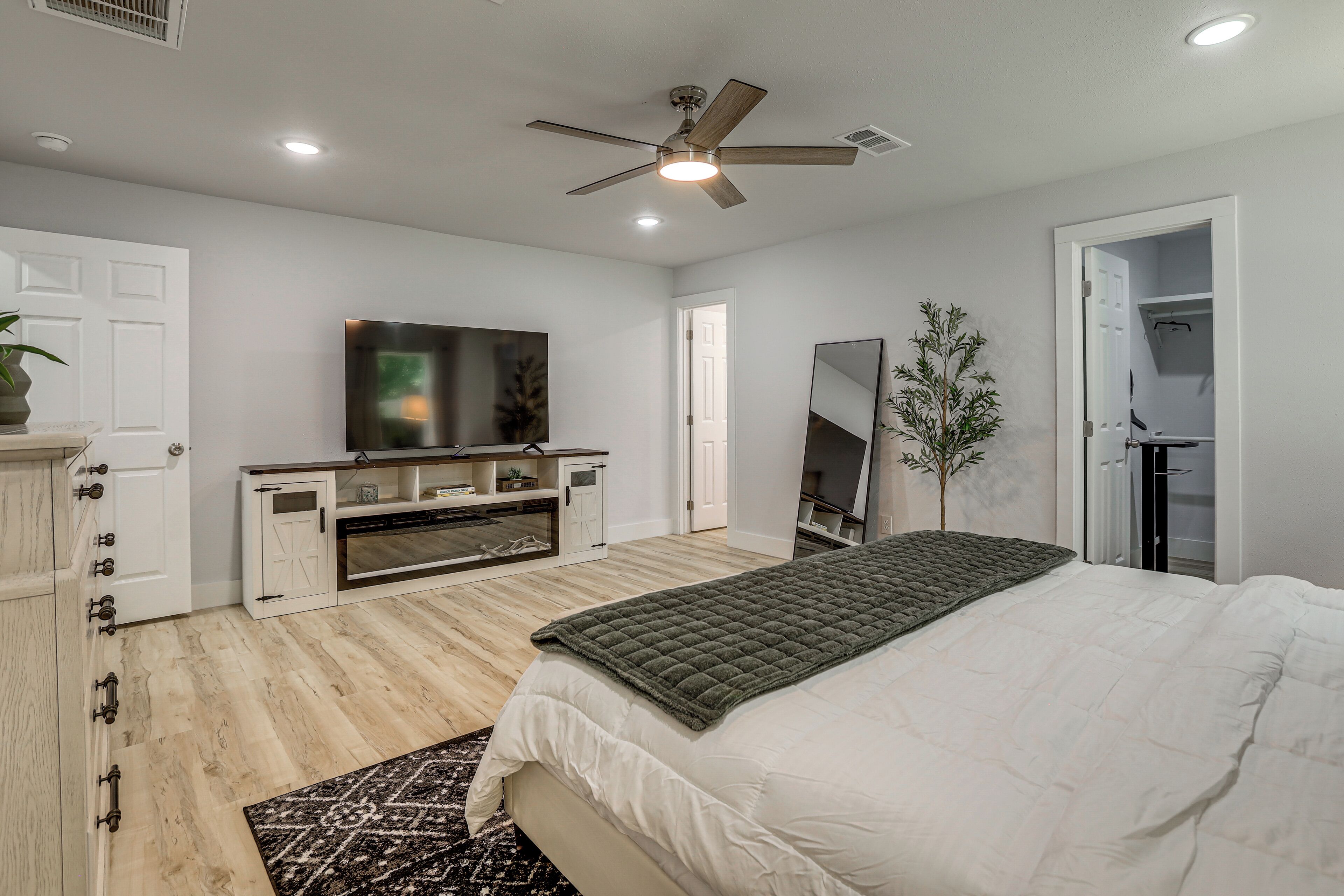 A bedroom with a bed, a TV, a ceiling fan, and a wardrobe.