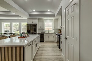 Una cocina moderna con armarios blancos, una isla central y vista al área de comedor.