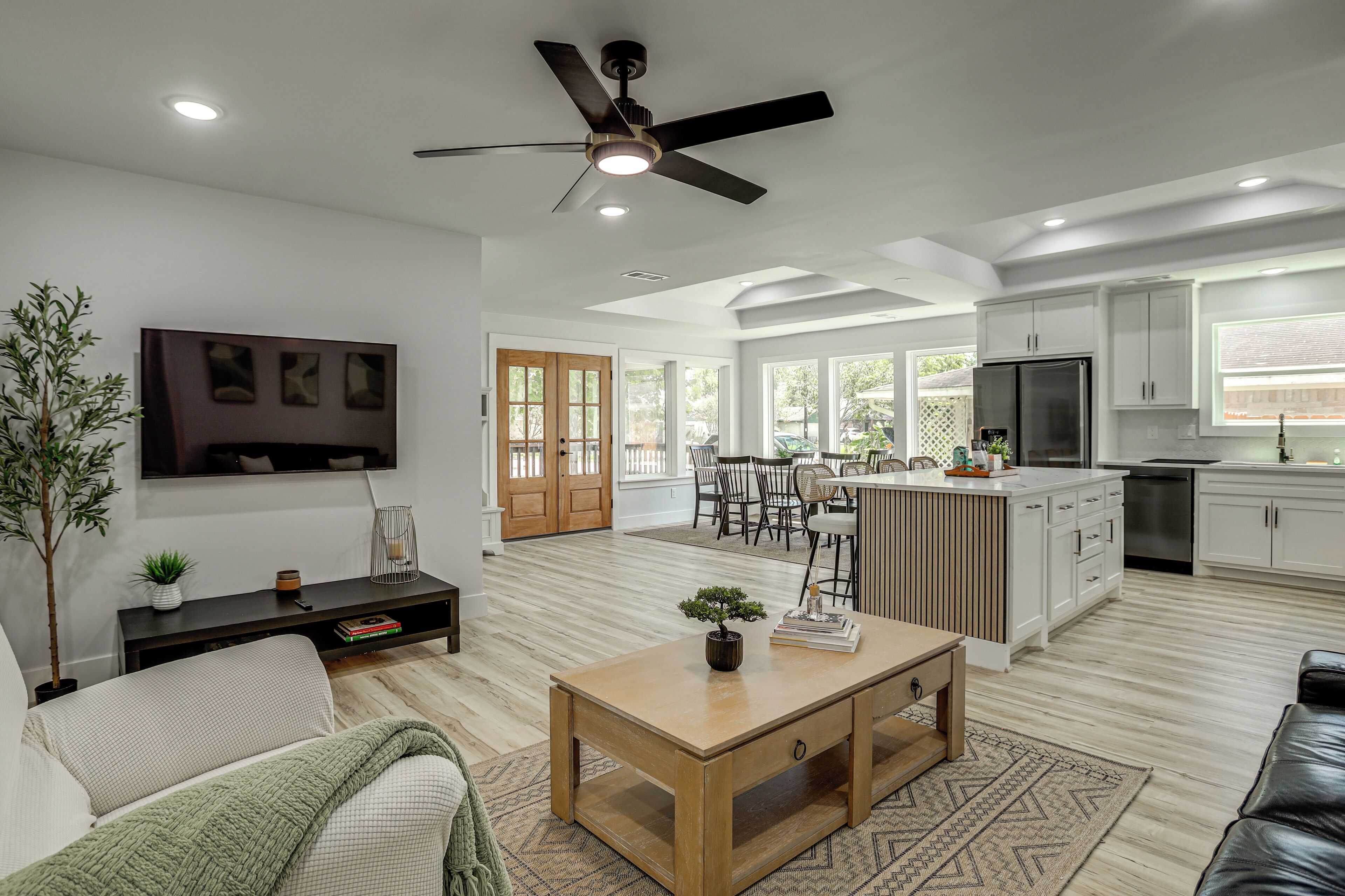A modern kitchen with white cabinets, a stainless steel refrigerator, and a dining area with a wooden table and chairs.