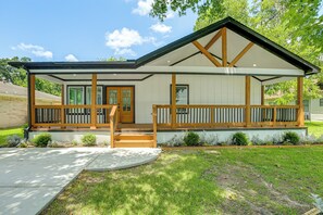 A modern two-story house with a covered porch, a front door, and a small front yard with a concrete path leading to the entrance.