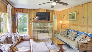 Ein gemütliches Wohnzimmer mit Kamin, Fernseher und einer Couch mit gemusterten Kissen.