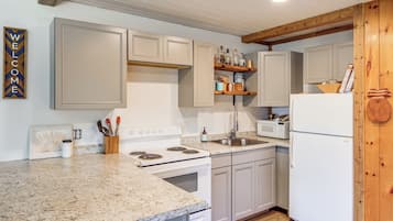 A kitchen with white cabinets, a granite countertop, a stove, a sink, and a microwave.