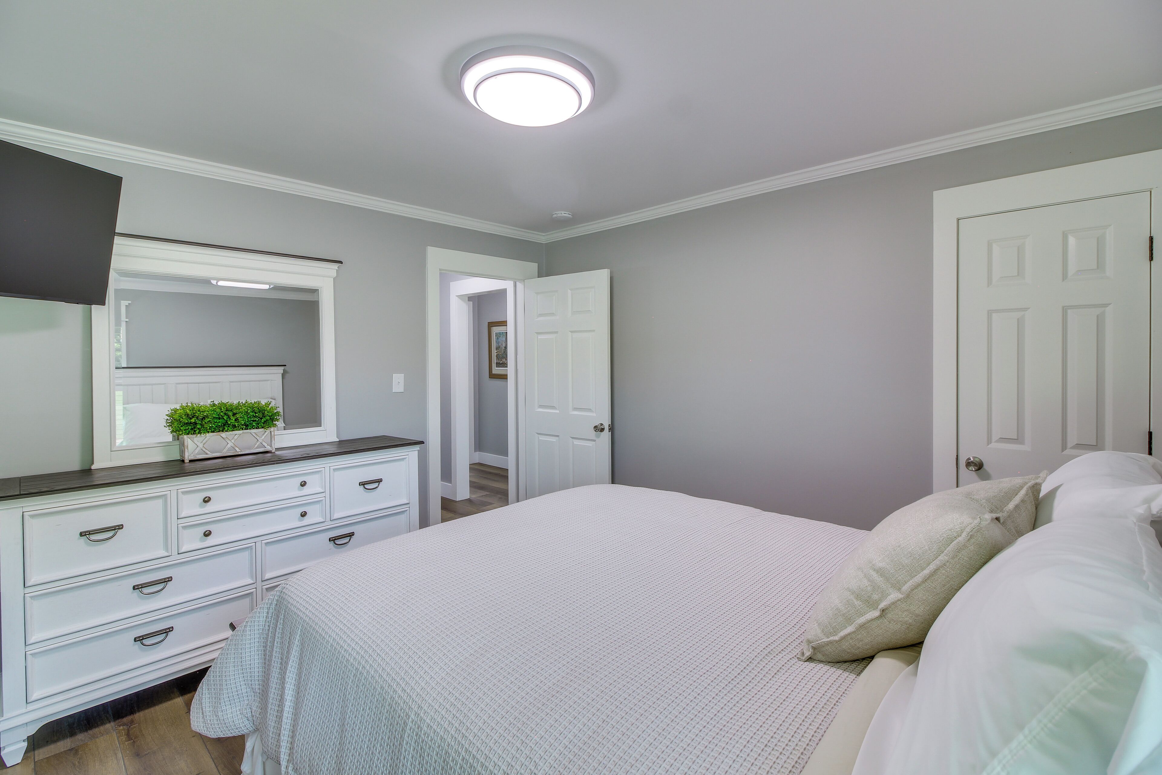 A bedroom with a bed, dresser, and a mirror.