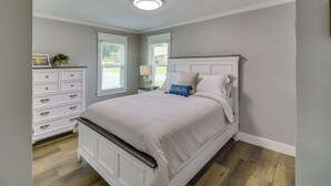 Ein Schlafzimmer mit Bett, Schminktisch und einem Fenster mit Jalousien.