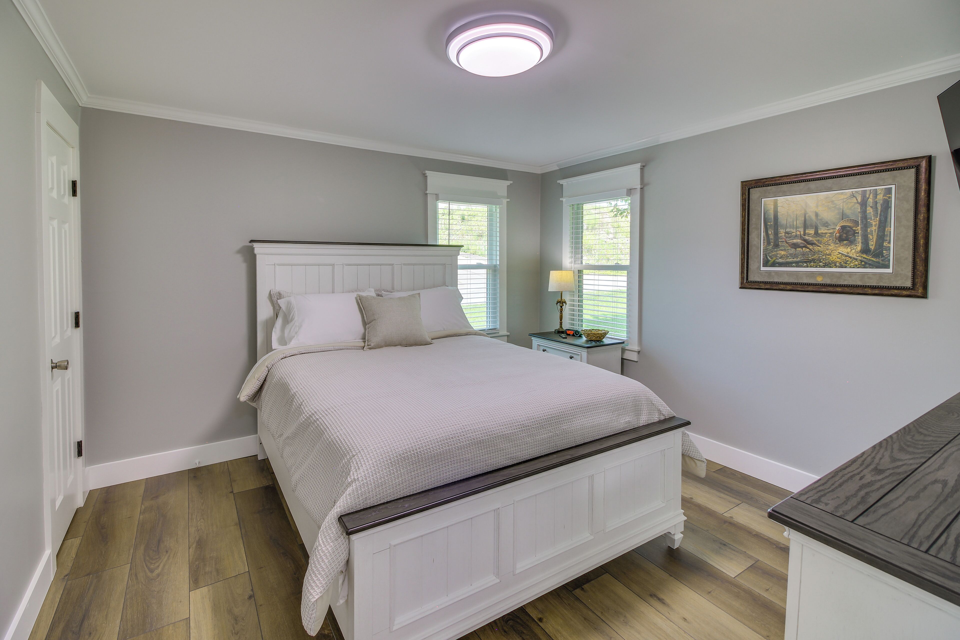 A bedroom with a bed, a nightstand, a lamp, and a framed picture on the wall.
