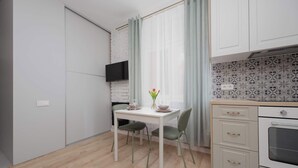 A compact kitchen with a dining area, a TV mounted on the wall, and a tiled backsplash. - Stylish Apartment for 4 People | Near the Theatre (Warszawa)