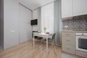 Eine kompakte Küche mit Essbereich, einem an der Wand montierten Fernseher und einer gefliesten Spritzschutzwand.