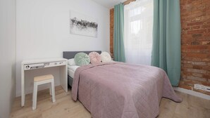 A bedroom with a bed, a desk, and a window with curtains. - Stylish Apartment for 4 People | Near the Theatre (Warszawa)
