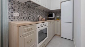 A kitchen with white cabinets, a built-in oven, a microwave, and a refrigerator. - Stylish Apartment for 4 People | Near the Theatre (Warszawa)