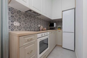 A kitchen with white cabinets, a built-in oven, a microwave, and a refrigerator.