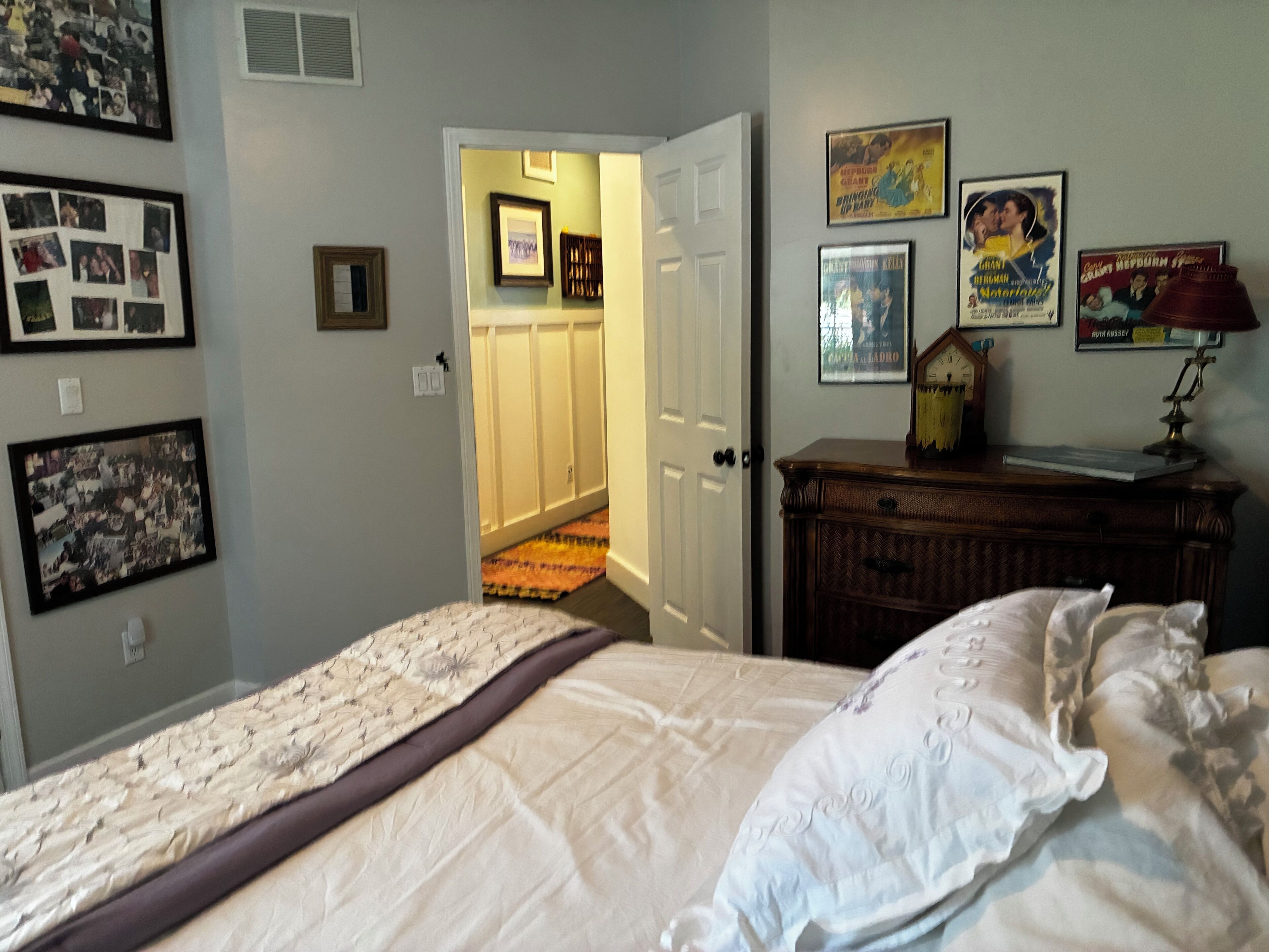 Une chambre à coucher comprenant un lit, une commode et une porte donnant sur un couloir.