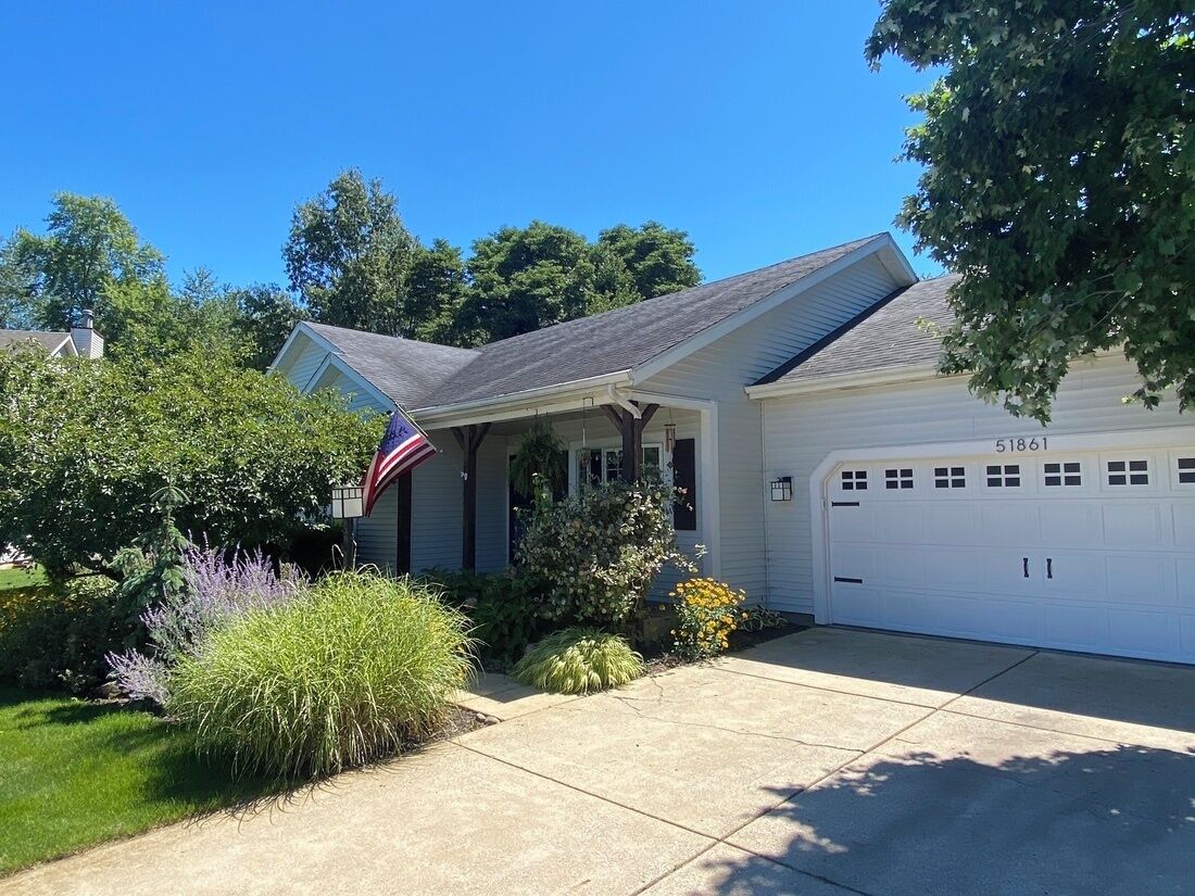 A residential house with a garage, a driveway, and a well-maintained lawn.