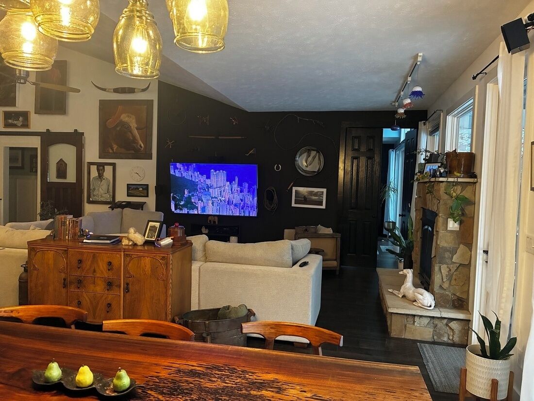 Un soggiorno con televisione, divano, mobiletto in legno e zona pranzo con tavolo e sedie.