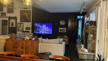 Un soggiorno con televisione, divano, mobiletto in legno e zona pranzo con tavolo e sedie.