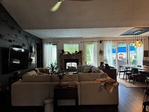 Olohuoneessa on sohva, taulutelevisio, takka sekä ruokailutila, jossa on pöytä ja tuolit.
