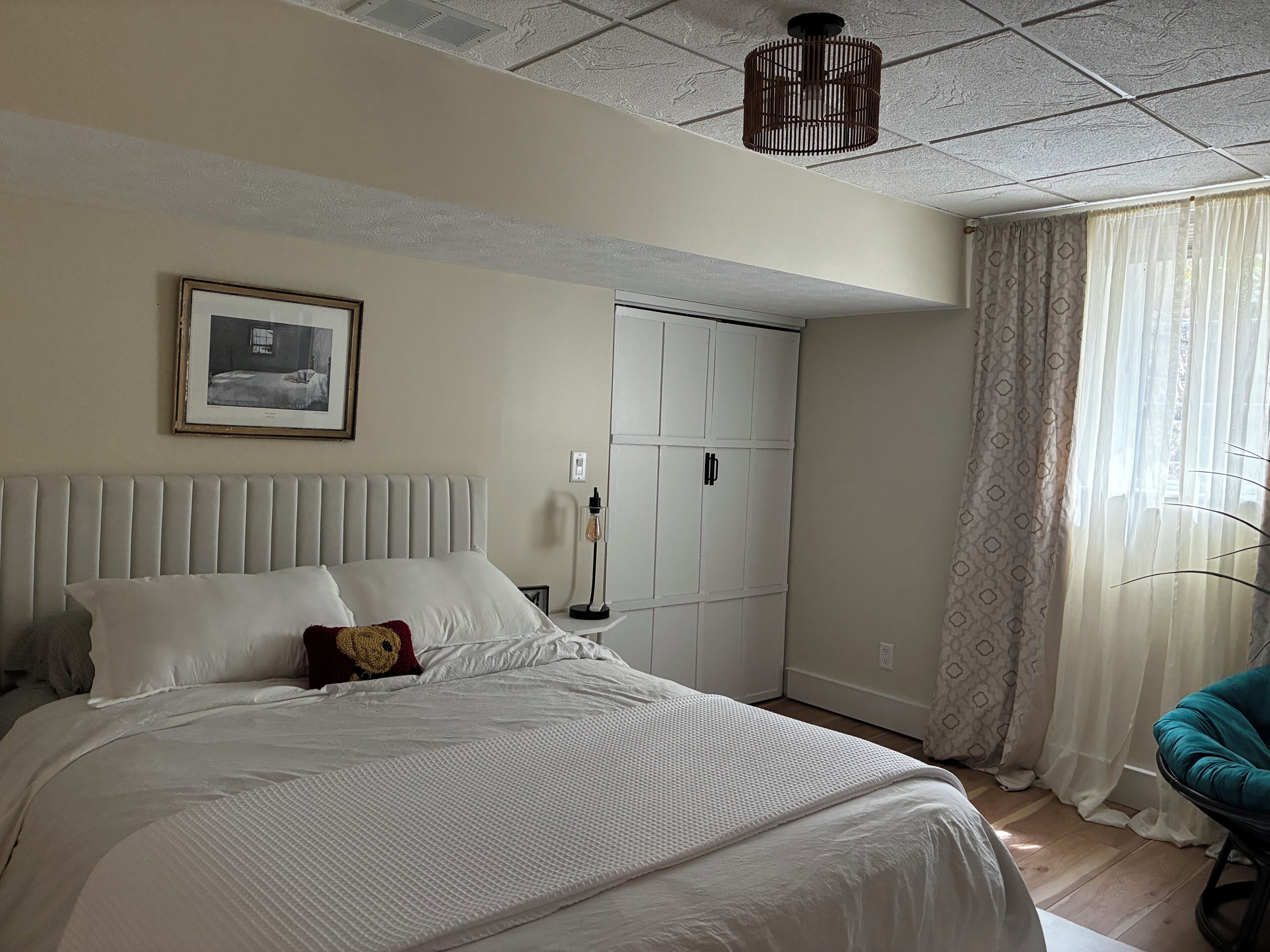 A hotel room with a bed, a wardrobe, a bedside lamp, and a window with curtains.