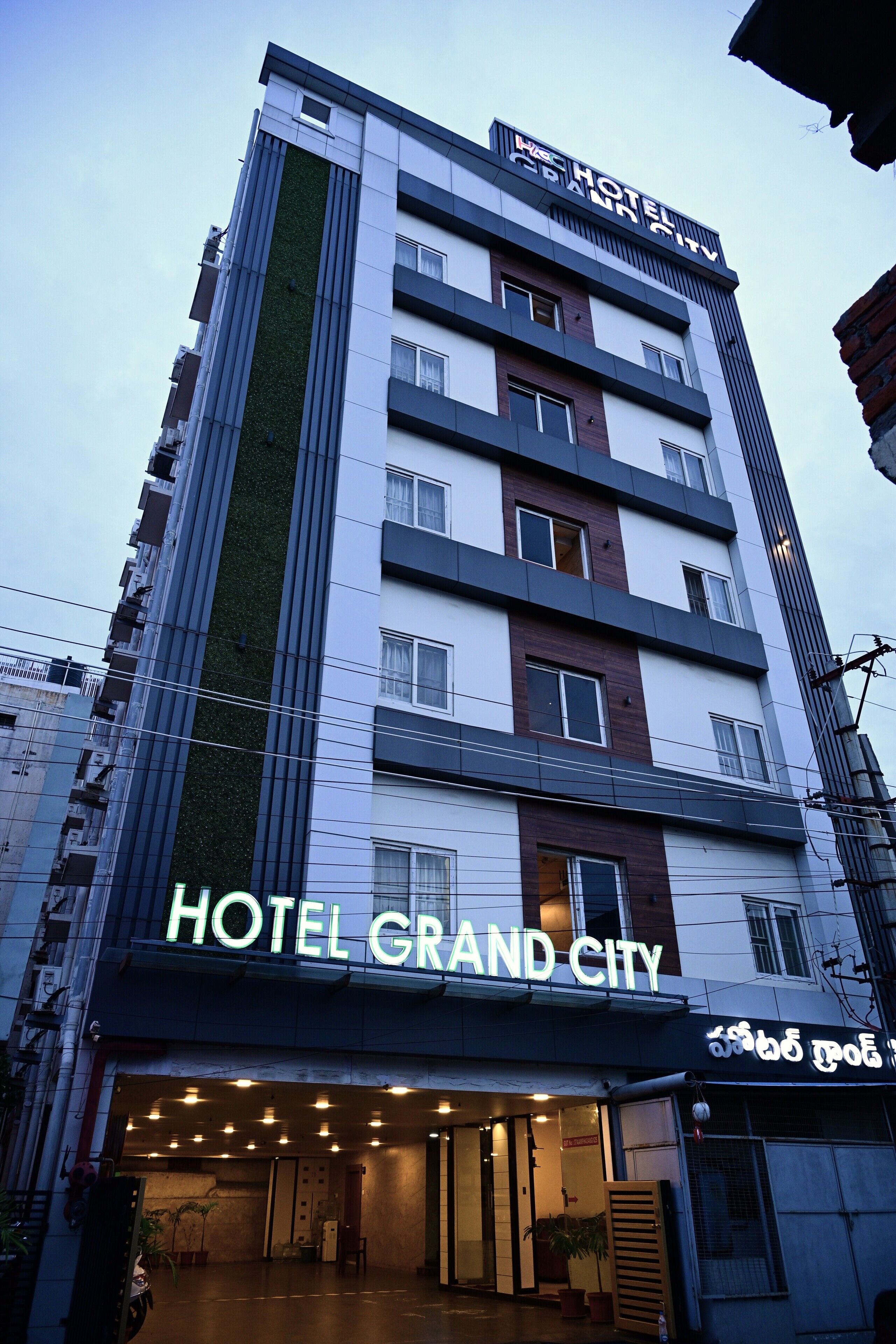 Een meerlaags hotelgebouw met een opvallend bord 'HOTEL GRAND CITY' op de begane grond.