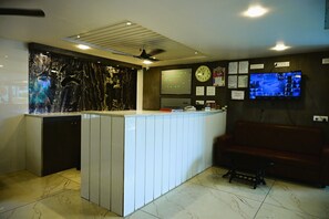 A reception area with a marble counter, a clock, and a television displaying security footage.
