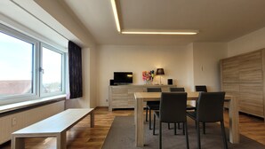 A modern dining area with a wooden table and chairs, a bench, and a television on a stand. - Apartment on the Coast for 6 People (Middelkerke)