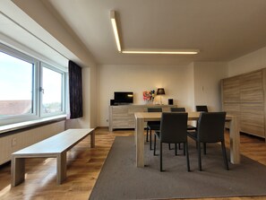 Ein stilvoller Essbereich mit einem Holztisch, Stühlen und einer Bank, sowie einem Fernseher auf einem Schrank.