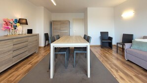 A modern living room with a wooden dining table, black chairs, a grey sofa, and a wooden cabinet with drawers. - Apartment on the Coast for 6 People (Middelkerke)
