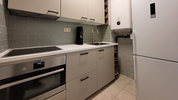 A modern kitchen with white cabinetry, a built-in oven, a coffee machine, and a Siemens refrigerator. - Apartment on the Coast for 6 People (Middelkerke)
