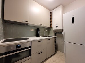 Eine moderne Küche mit weißen Schränken, einem eingebauten Ofen, einer Kaffeemaschine und einem Siemens-Kühlschrank.