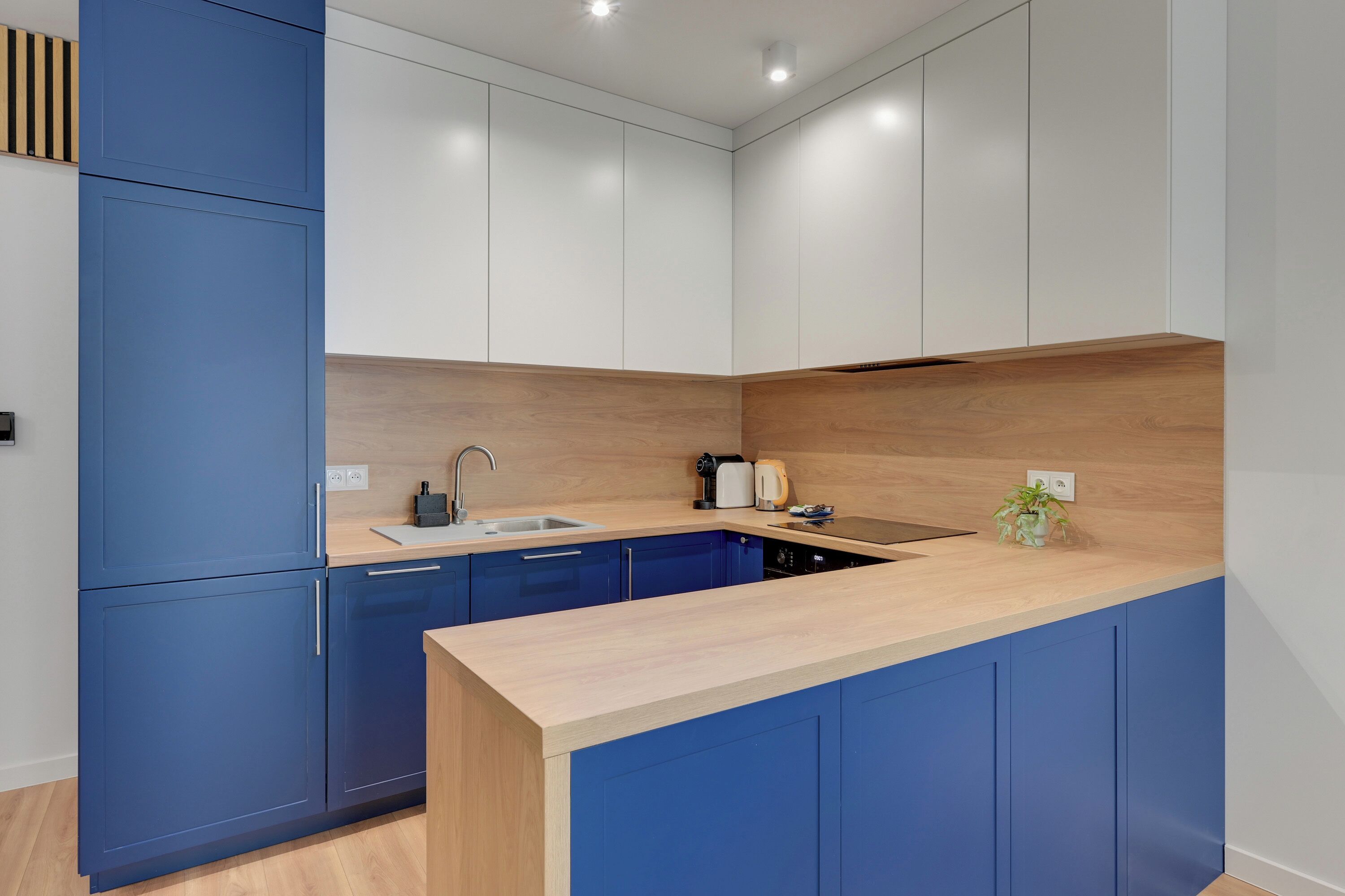 Una cocina moderna con armarios azules, encimera de madera y lavavajillas integrado.