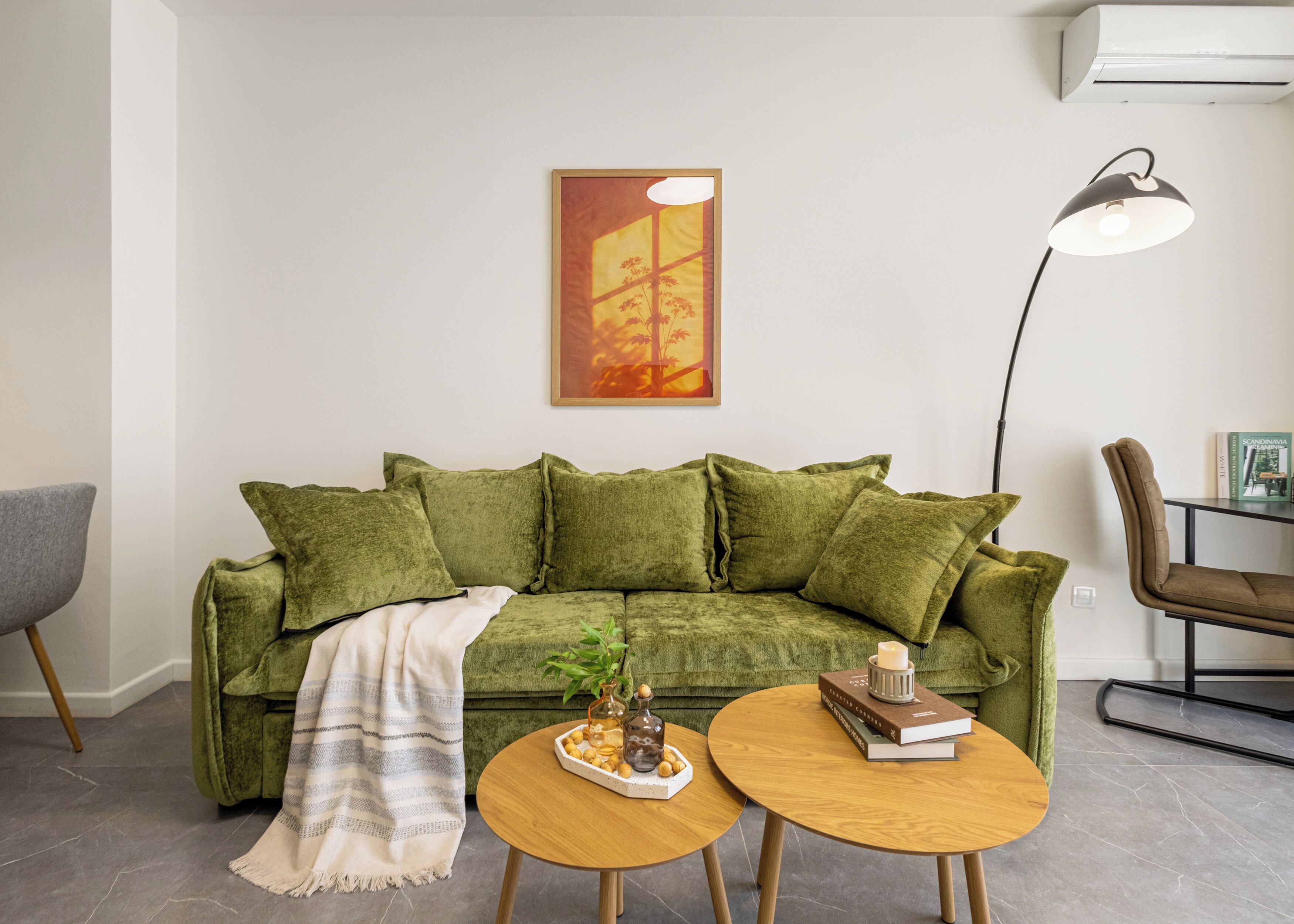 A living room with a green sofa, a coffee table, a floor lamp, and a painting on the wall.