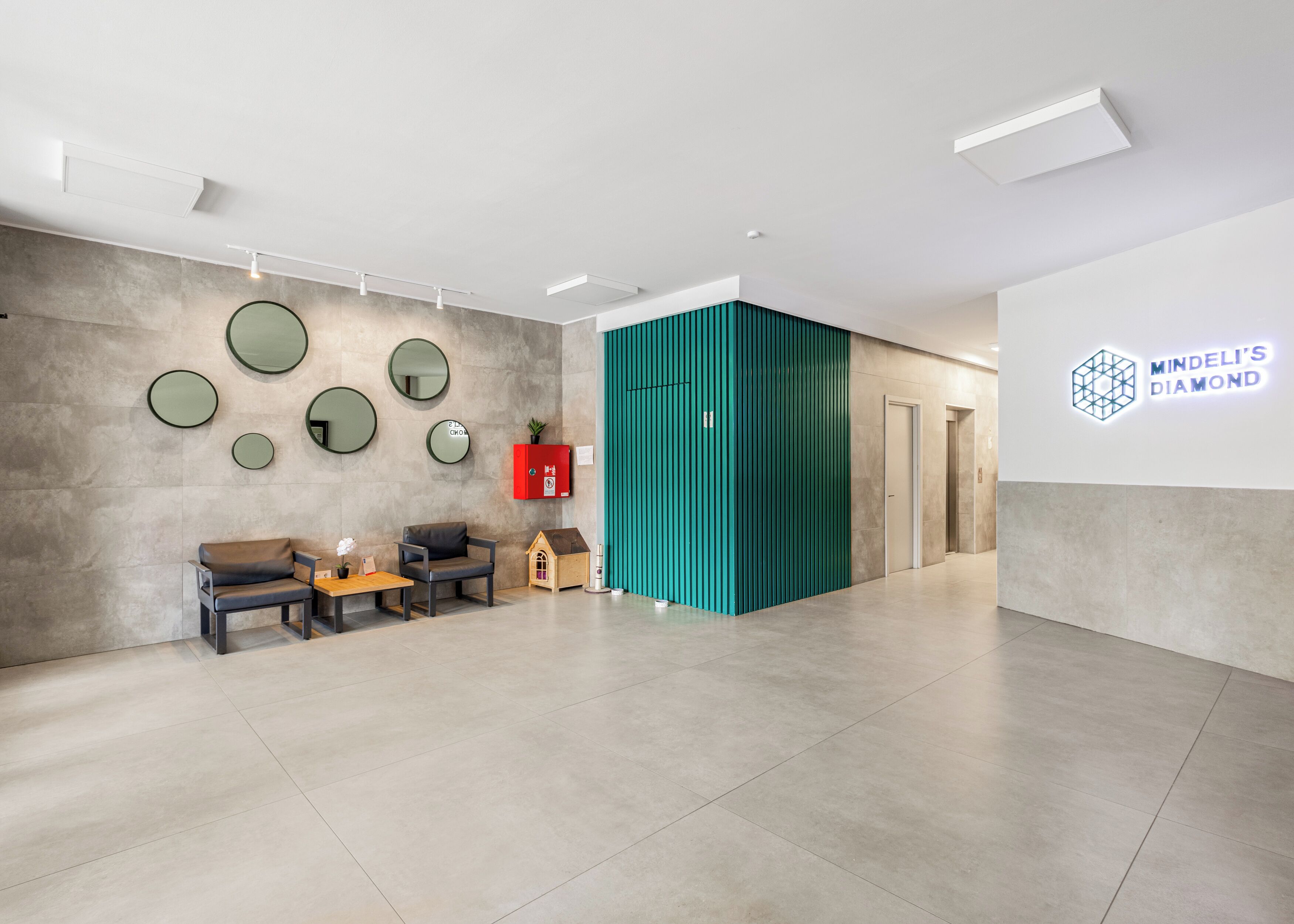 A modern interior with a reception desk, seating area, and a wall-mounted sign for 'Mindeli's Diamond'.