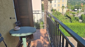 Un balcon avec une table et des chaises, un palmier et une vue sur des immeubles et des montagnes.