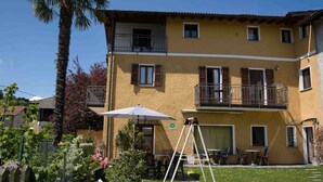 Un bâtiment à deux étages doté de balcons, d’un espace extérieur aménagé pour s’asseoir et d’une balançoire.