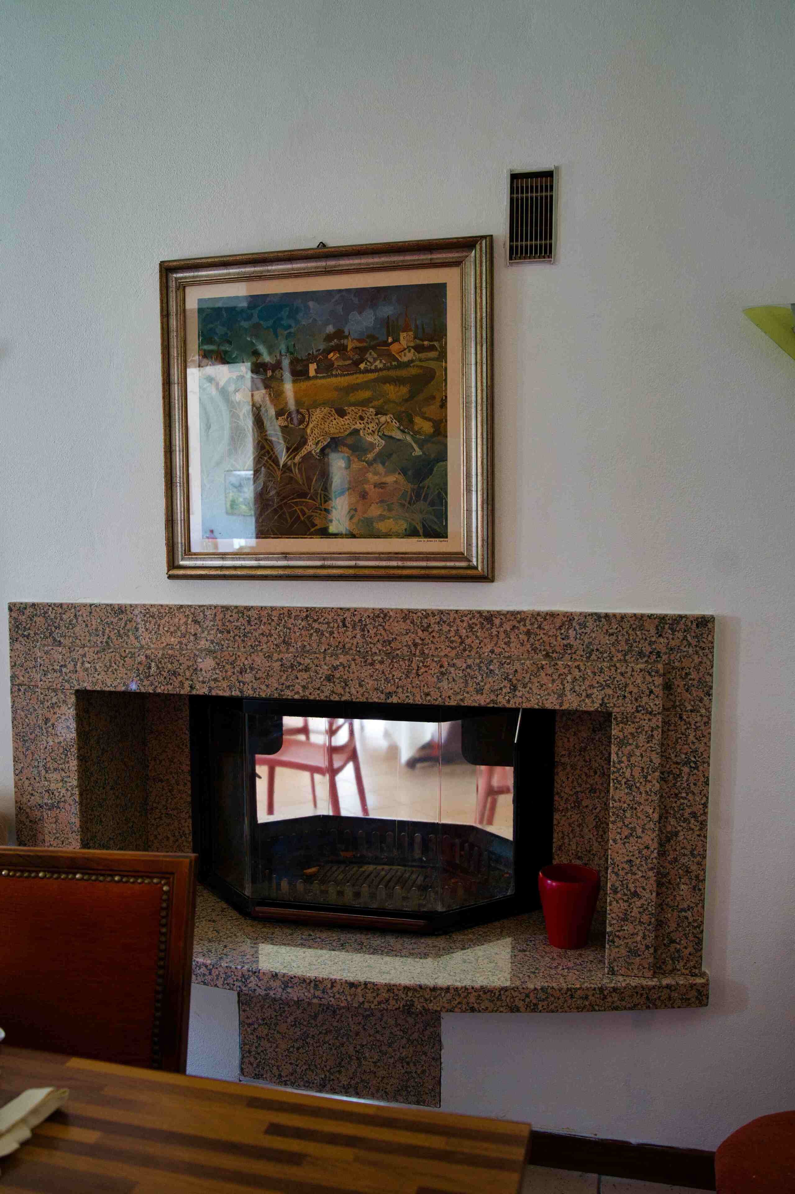 A fireplace with a framed painting above it.