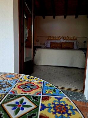 A room with a bed, a fan, and a tiled floor.