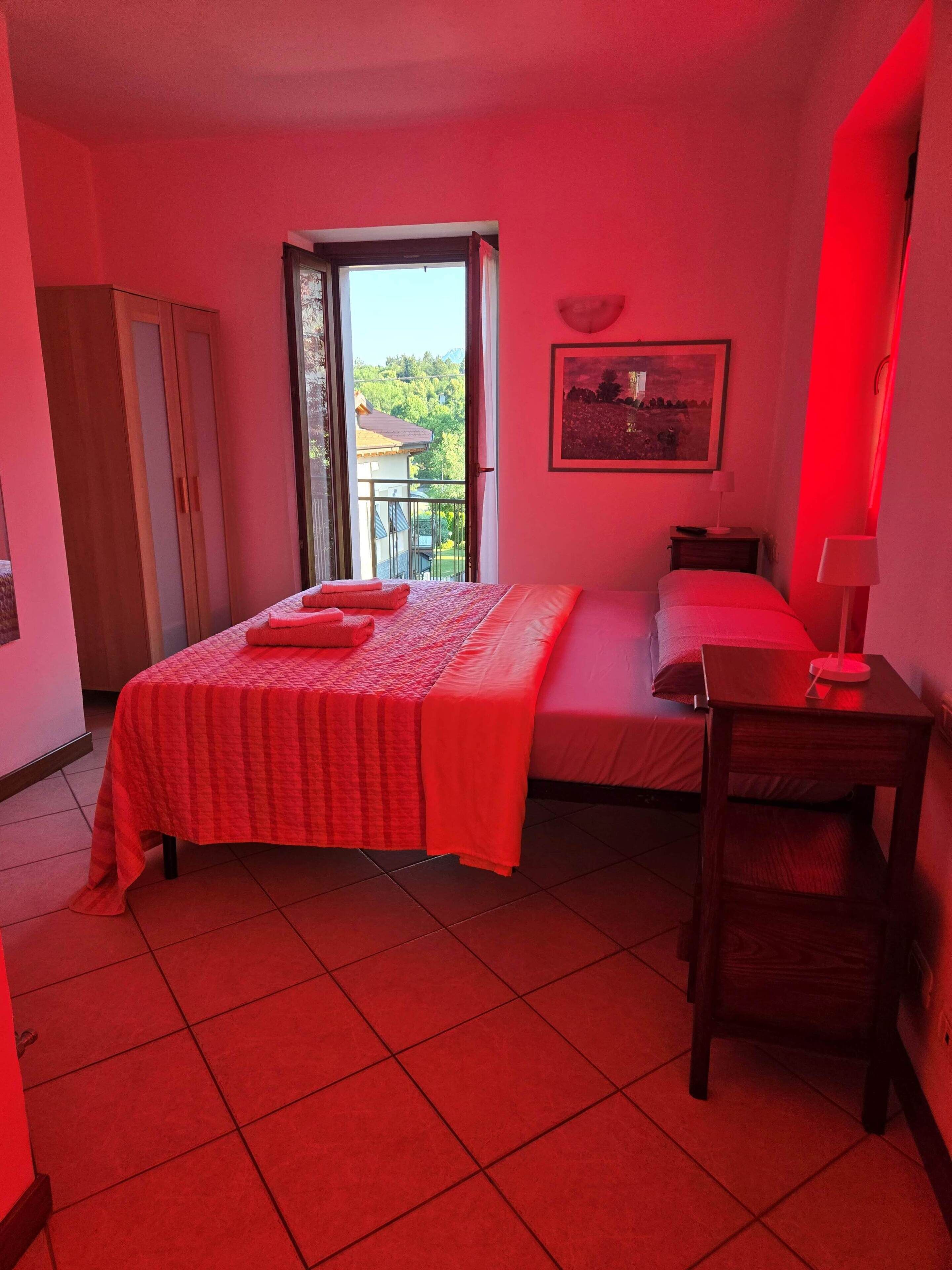 Ein Schlafzimmer mit einem Bett, einem Sessel, einem Nachttisch, einem Fenster und einer Tür.
