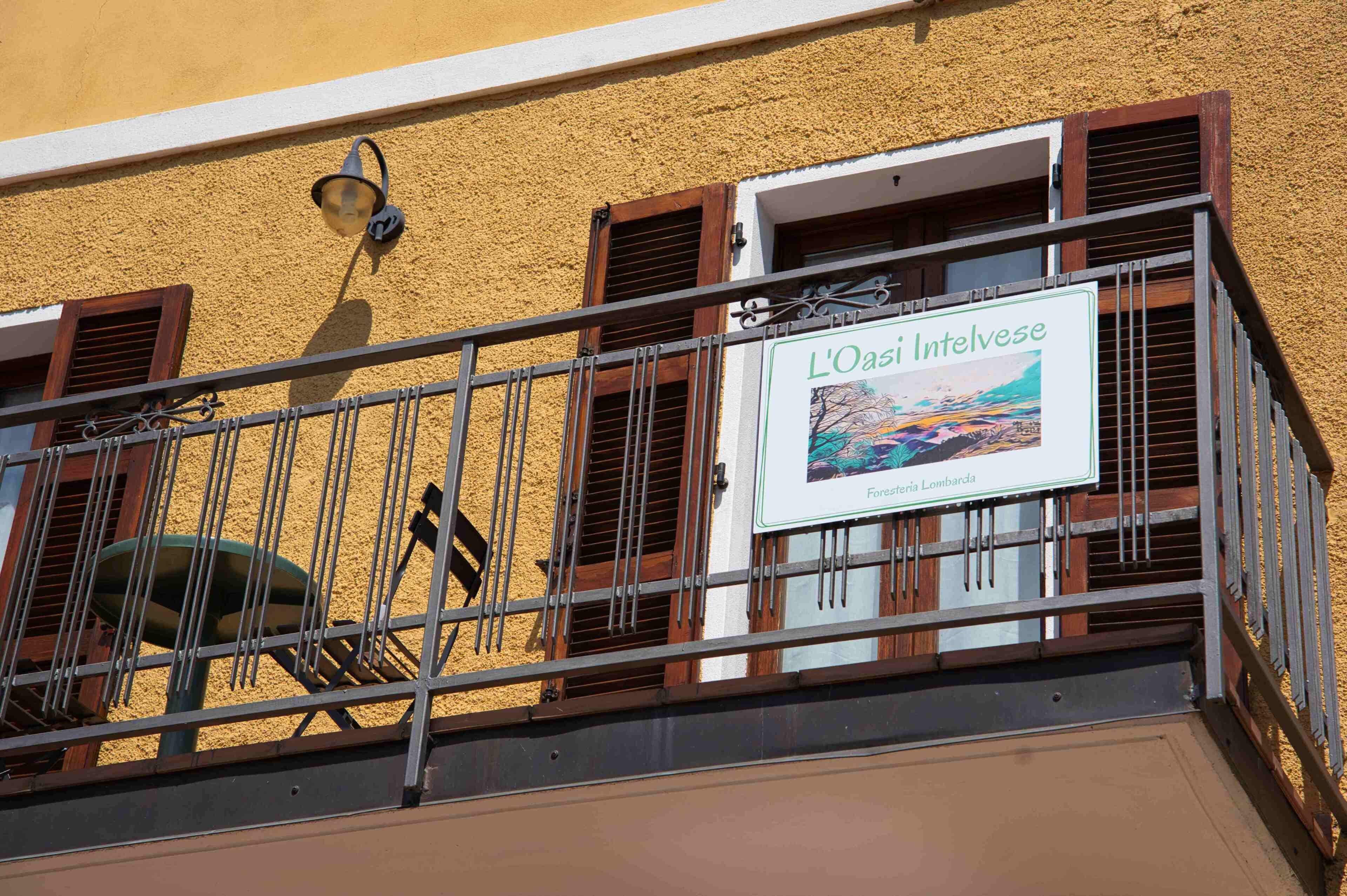 Un balcón con un cartel que dice 'L'Oasi Intelvise' y vistas del paisaje.