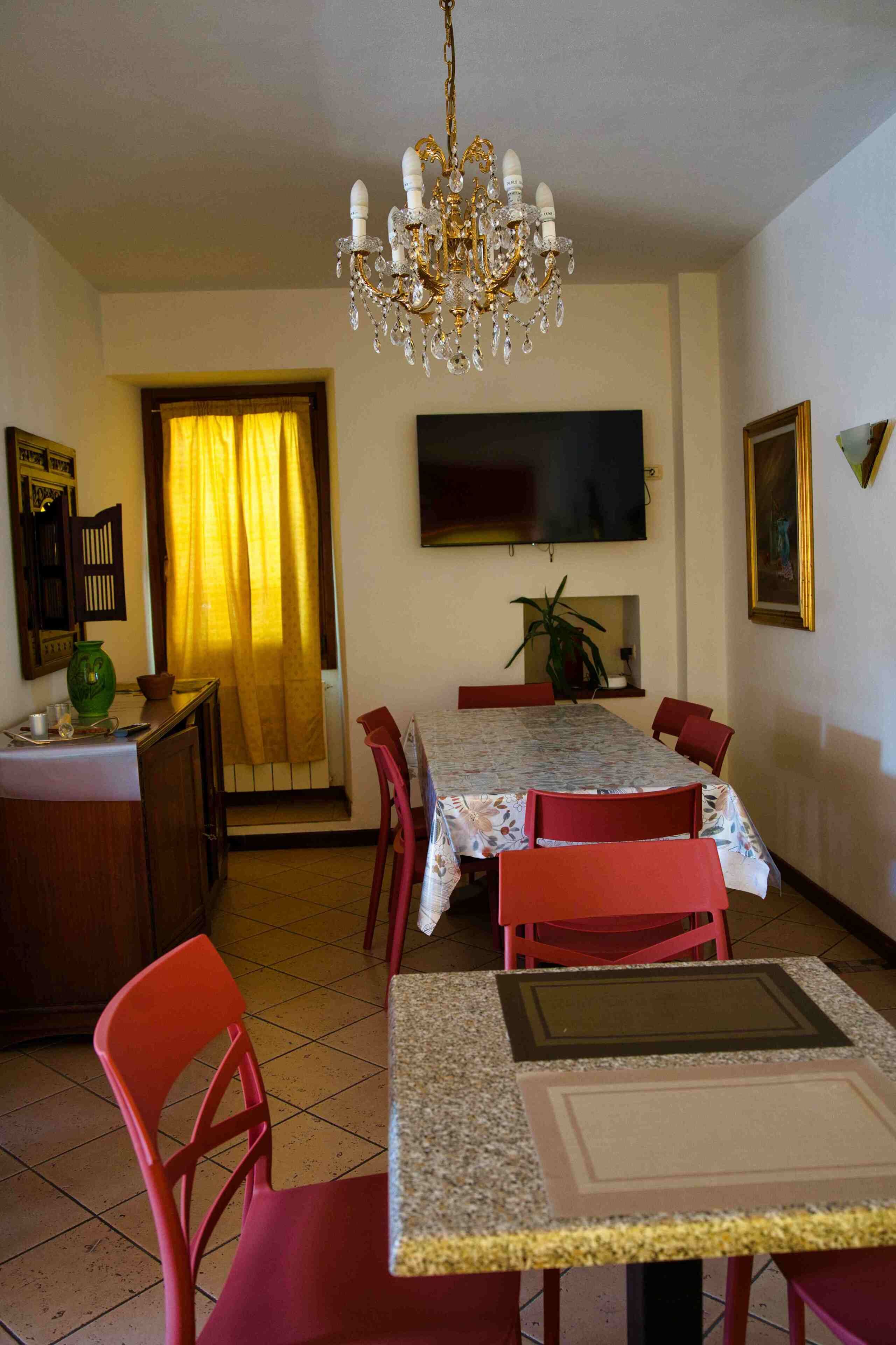 A dining area with a chandelier, a television, and a dining table with chairs.