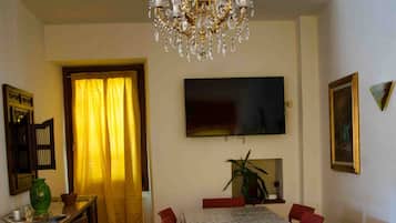 A dining area with a chandelier, a television, and a dining table with chairs.
