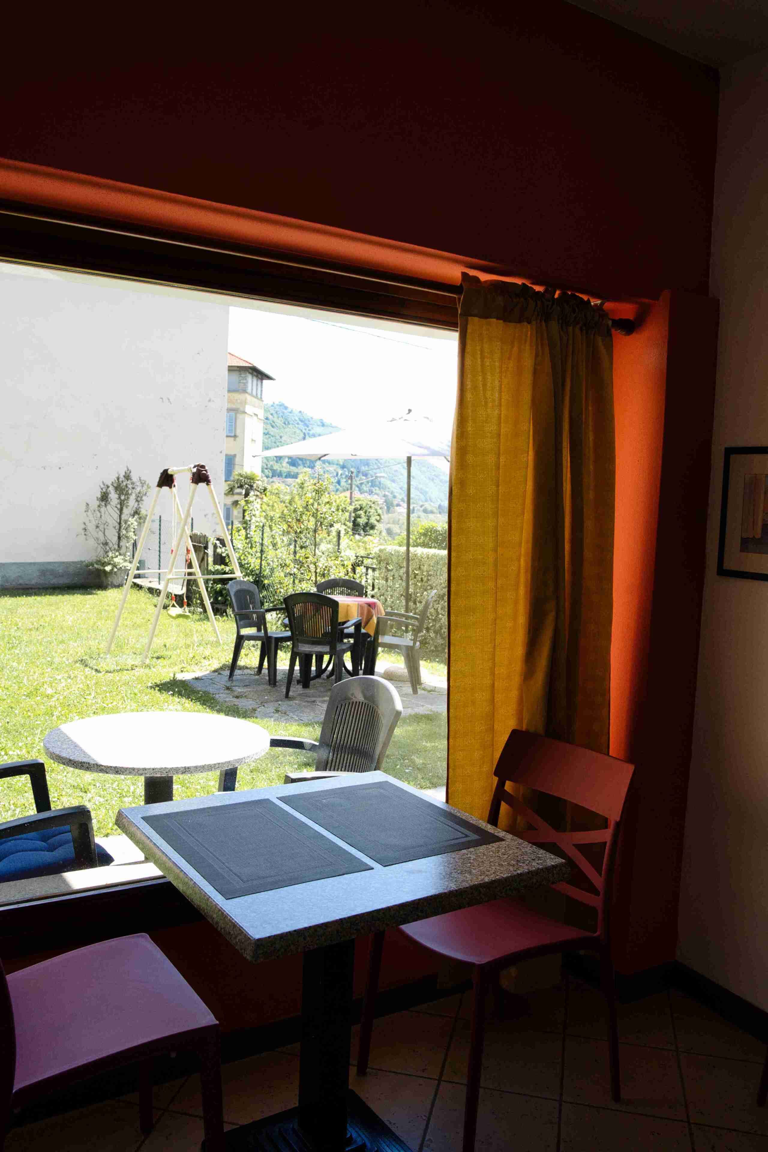 Una habitación con una mesa y sillas, una ventana con cortinas y vistas al exterior.