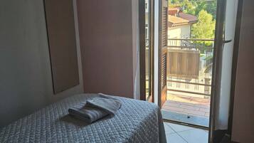 Un dormitorio con cama, ventana y vistas al exterior.