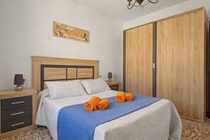 Quarto com cama, mesa de cabeceira, luminária, guarda-roupa e uma obra de arte na parede.