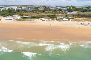 Eine Küstenlandschaft mit Sandstrand, einigen Gebäuden und blauem Himmel.
