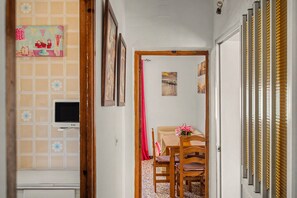 A hallway with a tiled wall, a television, a dining area with a table and chairs, and a door leading to another room. - El Rincón de Conil Apartment with Sea Views and Shared Terrace (Conil de la Frontera)