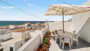 A rooftop terrace with a table and chairs, potted plants, and a view of the sea. - El Rincón de Conil Apartment with Sea Views and Shared Terrace (Conil de la Frontera)