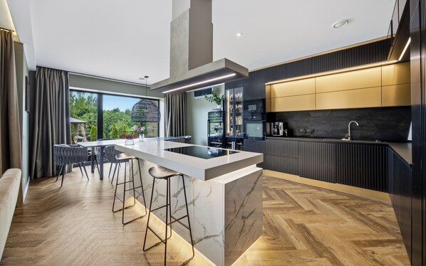 A modern kitchen with a central island, bar stools, and a dining area with a view.