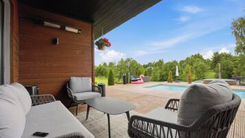 An outdoor patio with a pool, wicker furniture, and a wooden wall.
