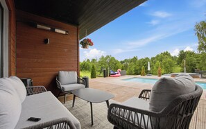 An outdoor patio with a pool, wicker furniture, and a wooden wall.