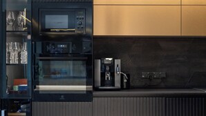 Een moderne keuken met een ingebouwde magnetron, oven en koffieapparaat.